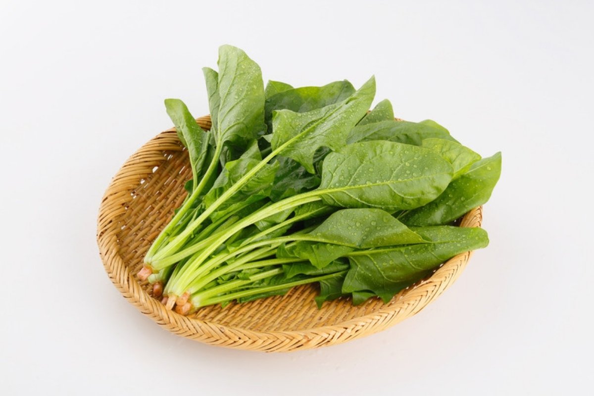 Fresh spinach leaves with their stems in a woven bamboo basket
