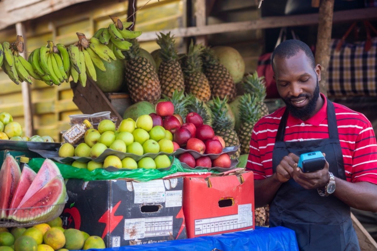Fruit vendor at a market stall using a handheld payment device