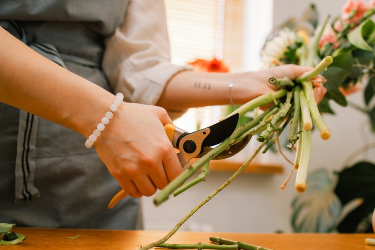 Florist cutting the stems of a bunch of fresh flowers with pruning shears