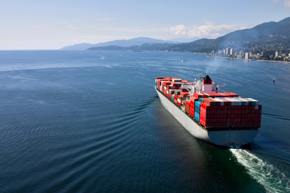 Nave carica di container impilati che esce da una baia